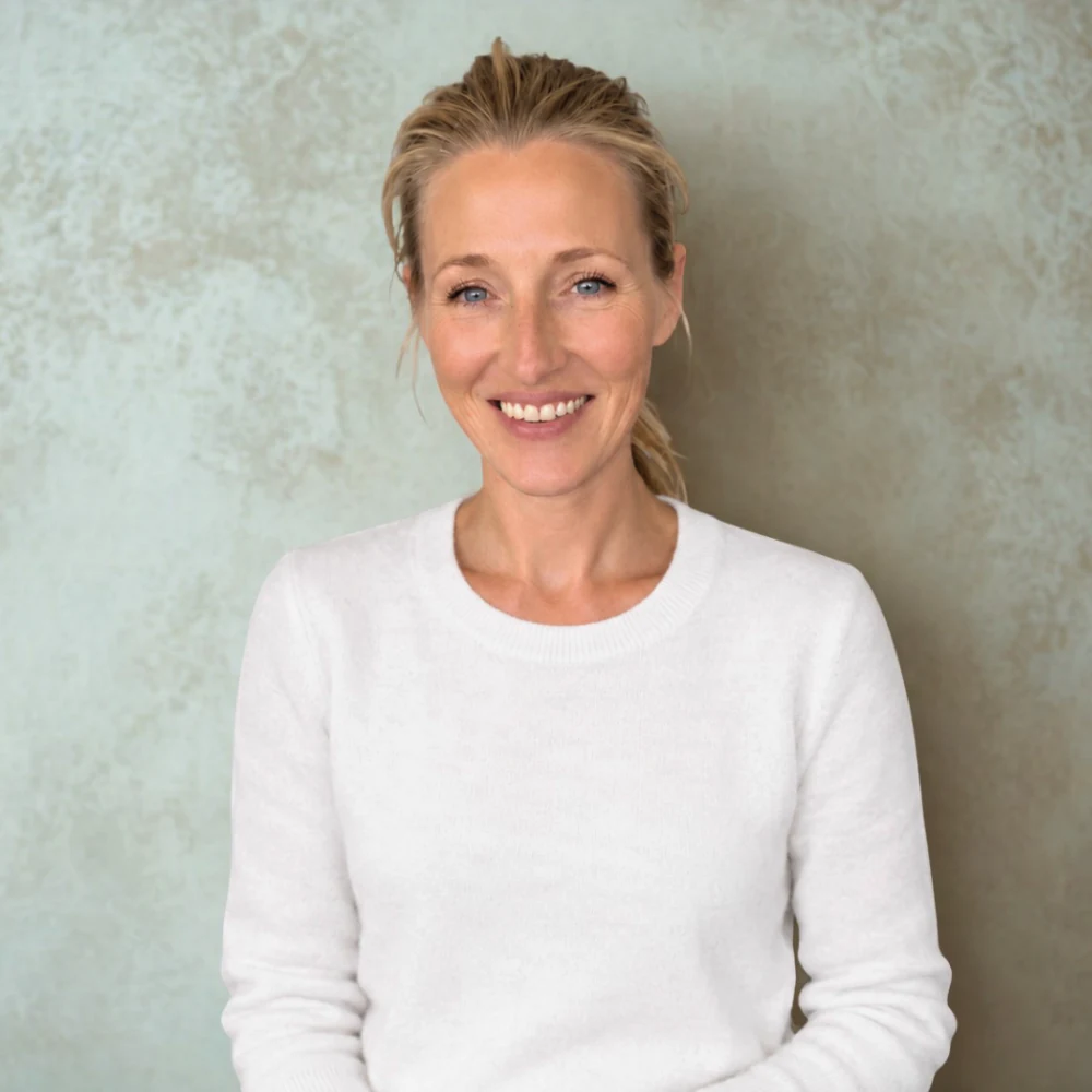 Ellie, the founder of The Ladybird Club, smiling in a white jumper against a soft green wall